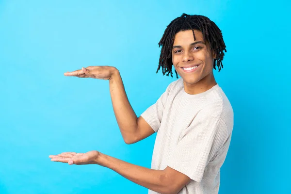 Jovem Afro Americano Sobre Fundo Azul Isolado Segurando Copyspace Para — Fotografia de Stock