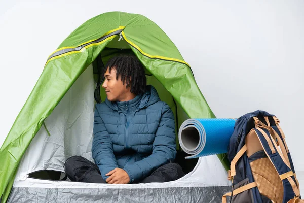 Young african american man inside a camping green tent in lateral position