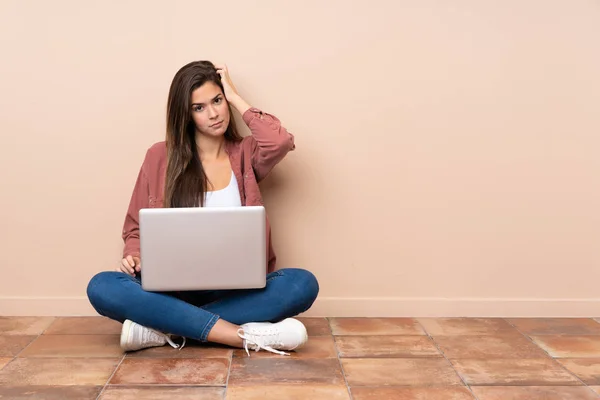 十几岁的女学生坐在地板上 带着沮丧和不理解的表情 带着笔记本电脑 — 图库照片