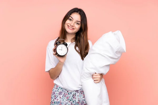 Mladá žena v pyžamu a držení vintage hodiny izolované na růžovém pozadí — Stock fotografie