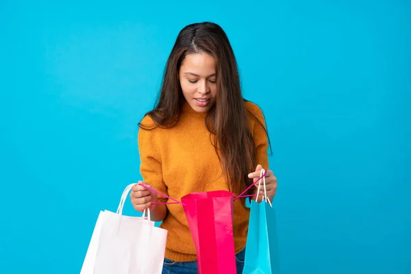 Ung Brasiliansk Flicka Över Isolerad Blå Bakgrund Håller Shoppingväskor Och — Stockfoto