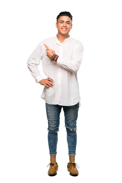 A full-length shot of a Young man pointing to the side to present a product over isolated white background