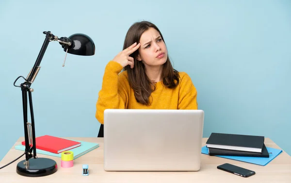 Student girl studying in her house isolated on blue background with problems making suicide gesture