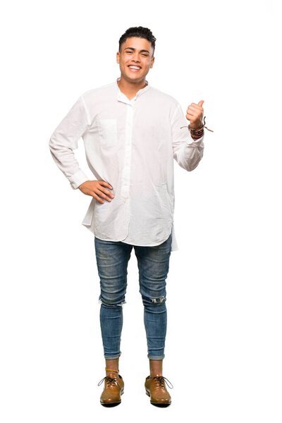 A full-length shot of a Young man pointing to the side to present a product over isolated white background