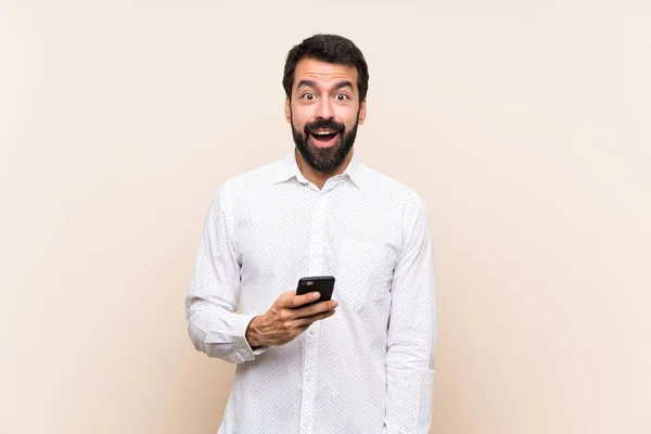 Junger Mann Mit Bart Hält Ein Handy Mit Überraschendem Gesichtsausdruck — Stockfoto
