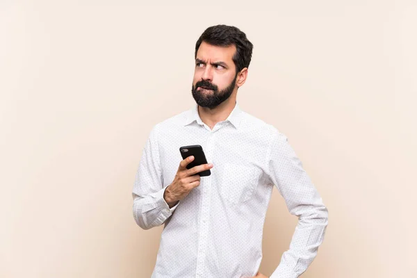 Jovem Com Barba Segurando Celular Com Expressão Facial Confusa — Fotografia de Stock