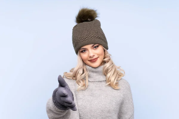 Kışlık Şapkalı Genç Kız Izole Edilmiş Mavi Arka Plan Tokalaşması — Stok fotoğraf