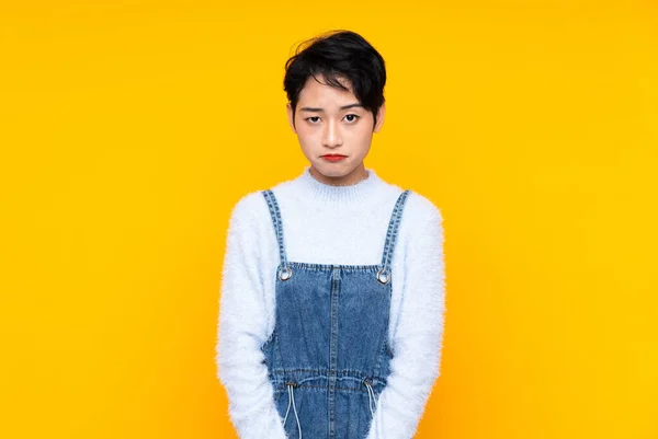 Junge Asiatische Mädchen Overalls Über Isoliertem Gelben Hintergrund Traurig — Stockfoto