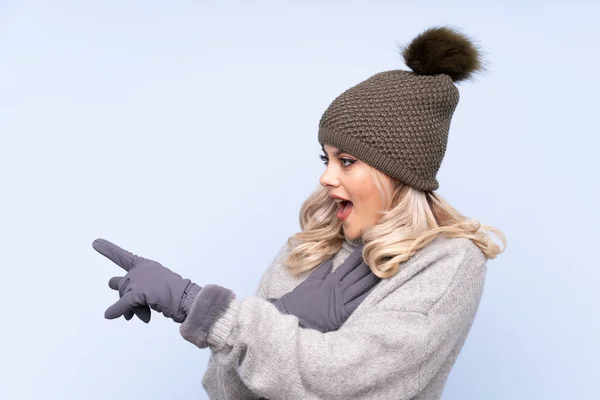 Giovane Ragazza Adolescente Con Cappello Invernale Sfondo Blu Isolato Puntando — Foto Stock