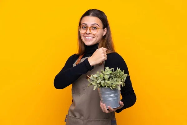 Menina Jardineiro Jovem Segurando Uma Planta Sobre Fundo Amarelo Isolado — Fotografia de Stock