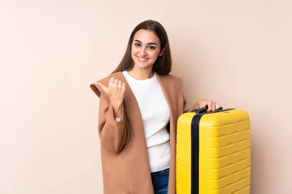 Traveler woman with suitcase pointing to the side to present a product