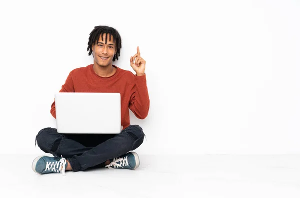 Joven Afroamericano Sentado Suelo Trabajando Con Portátil Mostrando Levantando Dedo —  Fotos de Stock