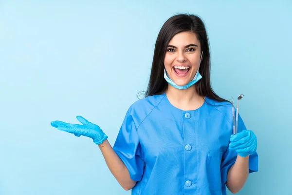 Junge Zahnärztin Hält Werkzeug Über Isolierten Blauen Hintergrund Und Hält — Stockfoto