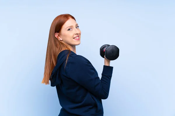 Junge Rothaarige Sportlerin Über Isolierten Blauen Hintergrund Machen Gewichtheben — Stockfoto
