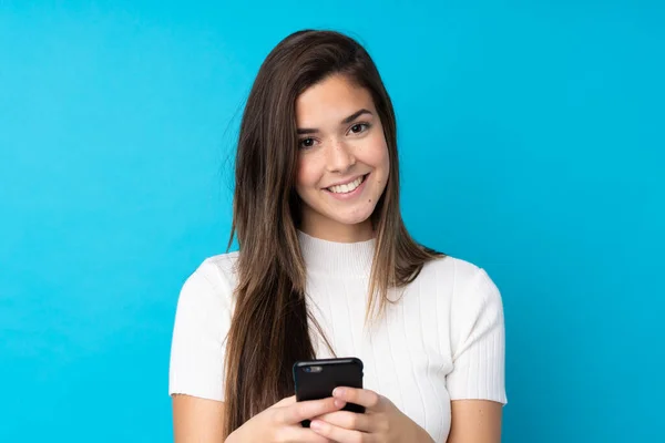 Adolescente Chica Sobre Aislado Azul Fondo Enviando Mensaje Con Móvil —  Fotos de Stock