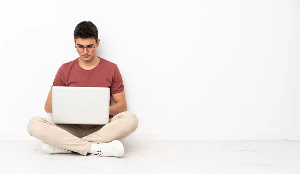 Adolescente homem sentado na flor com seu laptop — Fotografia de Stock