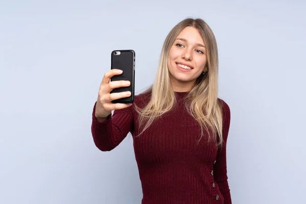 Joven Rubia Sobre Fondo Azul Aislado Haciendo Una Selfie —  Fotos de Stock