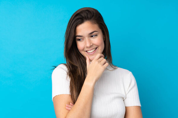 Девочка-подросток на изолированном синем фоне смотрит в сторону