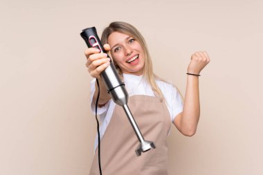 El blenderi kullanan genç sarışın kadın.