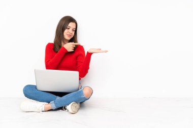 Beyaz arkaplan üzerinde bilgisayar ile çalışan tenaager kız bir reklam eklemek için avuç içi hayali kopyalama alanı tutuyor