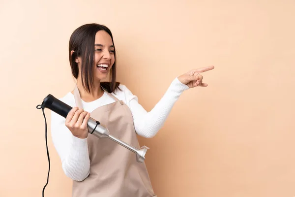 Jovem Morena Usando Liquidificador Mão Sobre Fundo Isolado Apontando Dedo — Fotografia de Stock