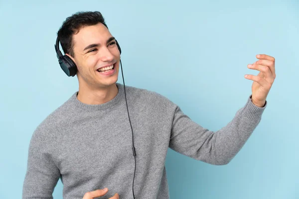 Νεαρός Καυκάσιος Όμορφος Άνδρας Απομονωμένος Μπλε Φόντο Ακούγοντας Μουσική Και — Φωτογραφία Αρχείου