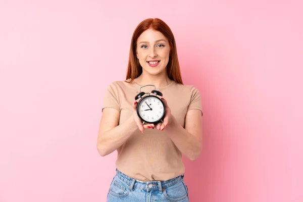 Jovem Ruiva Sobre Isolado Fundo Rosa Segurando Relógio Alarme Vintage — Fotografia de Stock