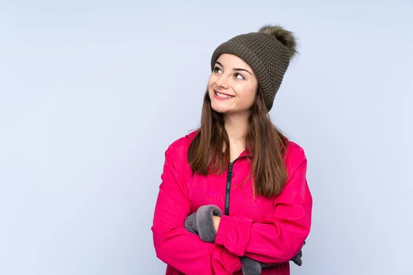 年轻姑娘头戴冬帽 蓝底孤零零地望着天空 — 图库照片