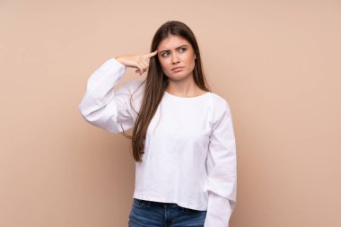 Izole arka plan üzerinde genç kız kafasına parmak koyarak delilik jest yapma