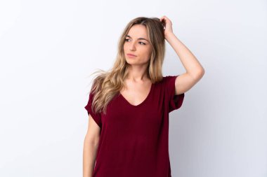 İzole edilmiş beyaz arka planı olan genç bir kadın kafasını kaşırken şüpheye düşüyor.