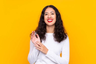 Karışık ırk kadını, izole edilmiş sarı arka planda alkışlıyor.