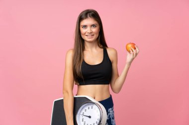 Tartı makinesi olan genç bir kız ve izole edilmiş bir elma.