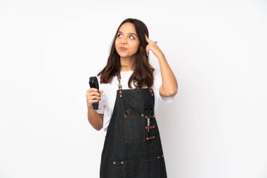 Beyaz arka planda izole edilmiş genç kuaför kadının şüpheleri ve düşünceleri var.