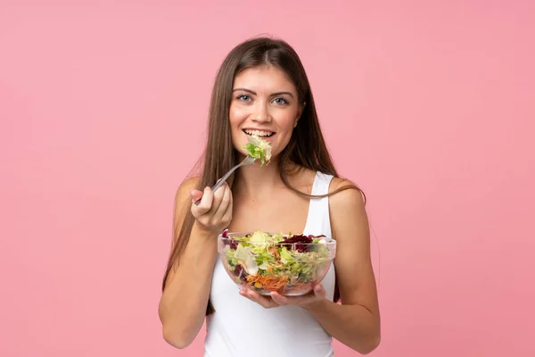 Junge Frau mit Salat über isolierte rosa Wand — Stockfoto