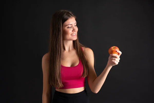 Ung sport kvinna med ett äpple över isolerad svart bakgrund — Stockfoto