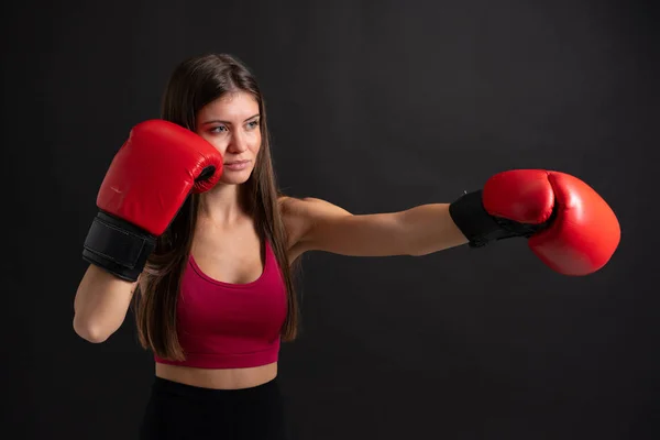 Jovem mulher esporte com luvas de boxe sobre fundo preto isolado — Fotografia de Stock