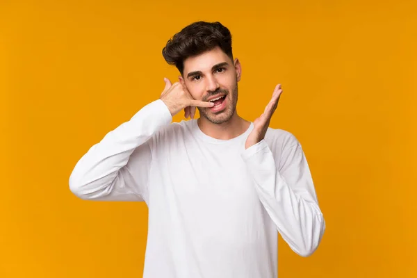 Jongeman Geïsoleerde Oranje Achtergrond Maken Telefoon Gebaar Twijfelen — Stockfoto