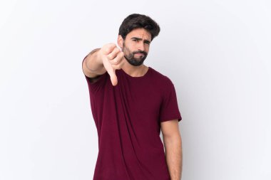 Sakallı, beyaz arka planda genç ve yakışıklı bir adam olumsuz bir ifadeyle baş parmağını aşağı gösteriyor.