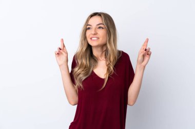 İzole edilmiş beyaz arka planı olan genç bir kadın parmaklarını çapraz yapıp en iyisini diliyor.