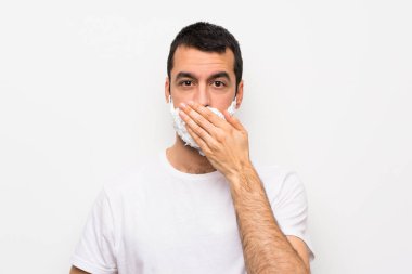 Sakalını kesen bir adam izole edilmiş beyaz arka planda ağzı elleriyle kapatıyor.