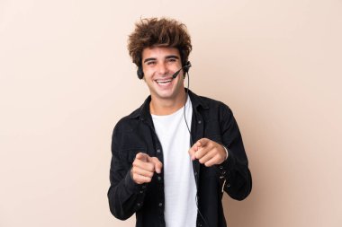 Kulaklıkla çalışan pazarlamacı adam izole edilmiş arka plan noktalarından sana parmak atıyor.