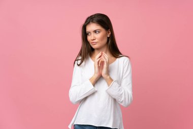 Soyutlanmış pembe arka plan entrikaları kuran genç bir kadın.