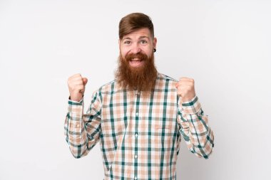 Kızıl saçlı, uzun sakallı, soyutlanmış beyaz arka planlı bir adam galibiyeti kutluyor.