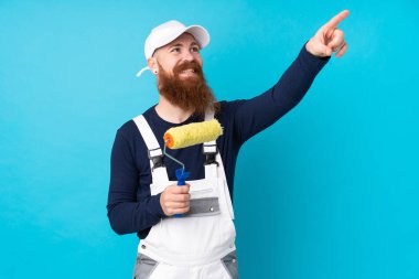 Uzun sakallı ressam mavi arka planda şeffaf ekrana dokunuyor.