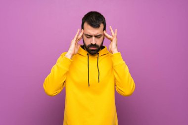 Başı ağrıyan sarı kazaklı yakışıklı bir adam.