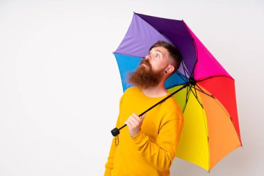 Kızıl saçlı, uzun sakallı, şemsiyeli bir adam.