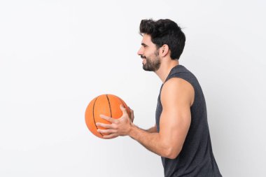 Sakallı, beyaz arka planda basketbol oynayan yakışıklı bir genç.