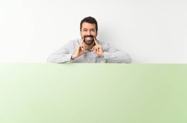 Sakallı genç yakışıklı adam elinde kocaman boş bir pankart mutlu ve hoş bir ifadeyle gülümsüyor.