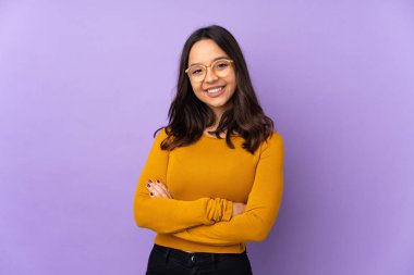 Mor arka planda izole edilmiş genç melez kadın kollarını ön cephede çapraz tutuyor.