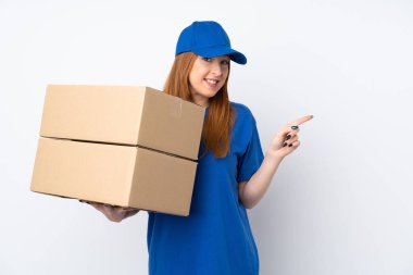 İzole edilmiş beyaz arka planda genç teslimatçı kadın parmağını yana doğru gösteriyor.